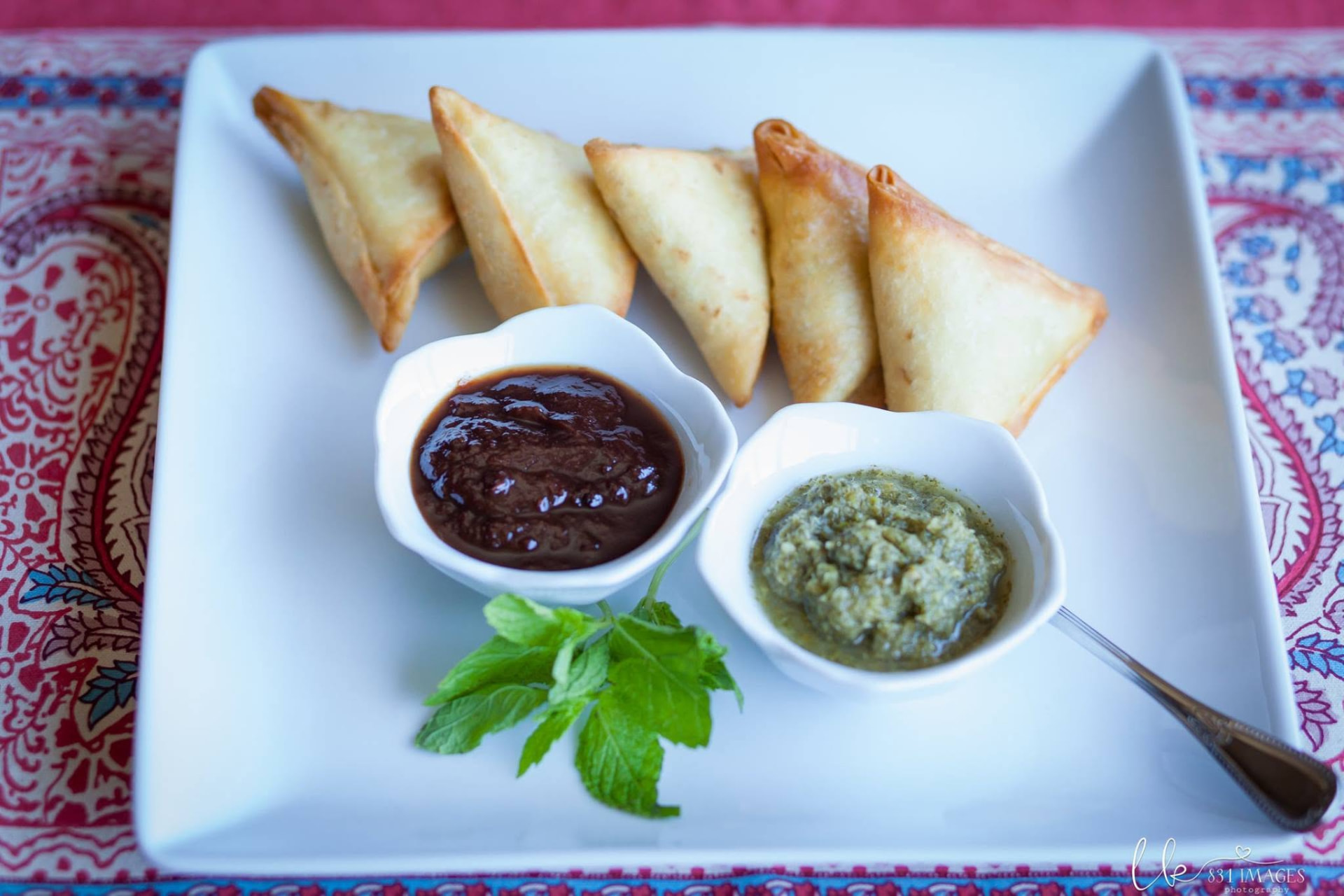 Samosas plated with tamarind and mint chutneys
