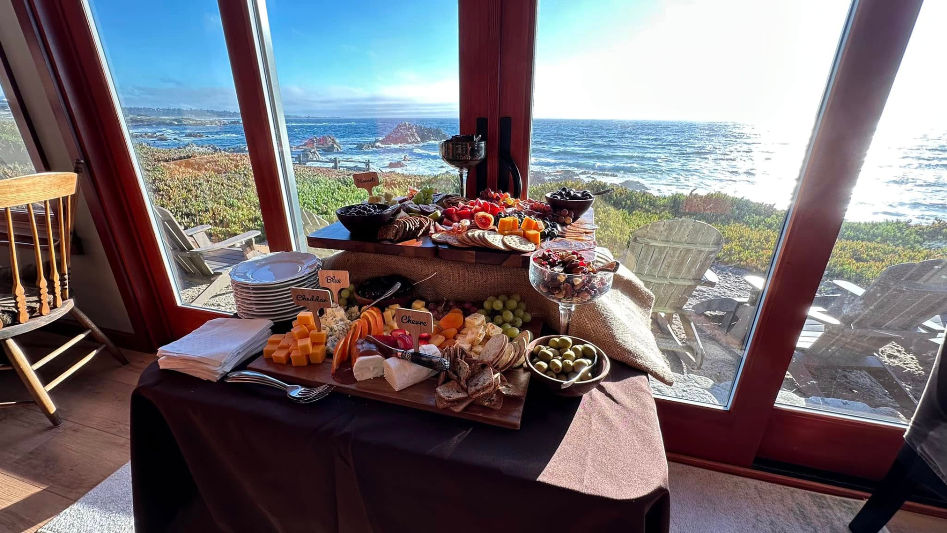 Cheese and charcuterie display in front of oceanfront windows